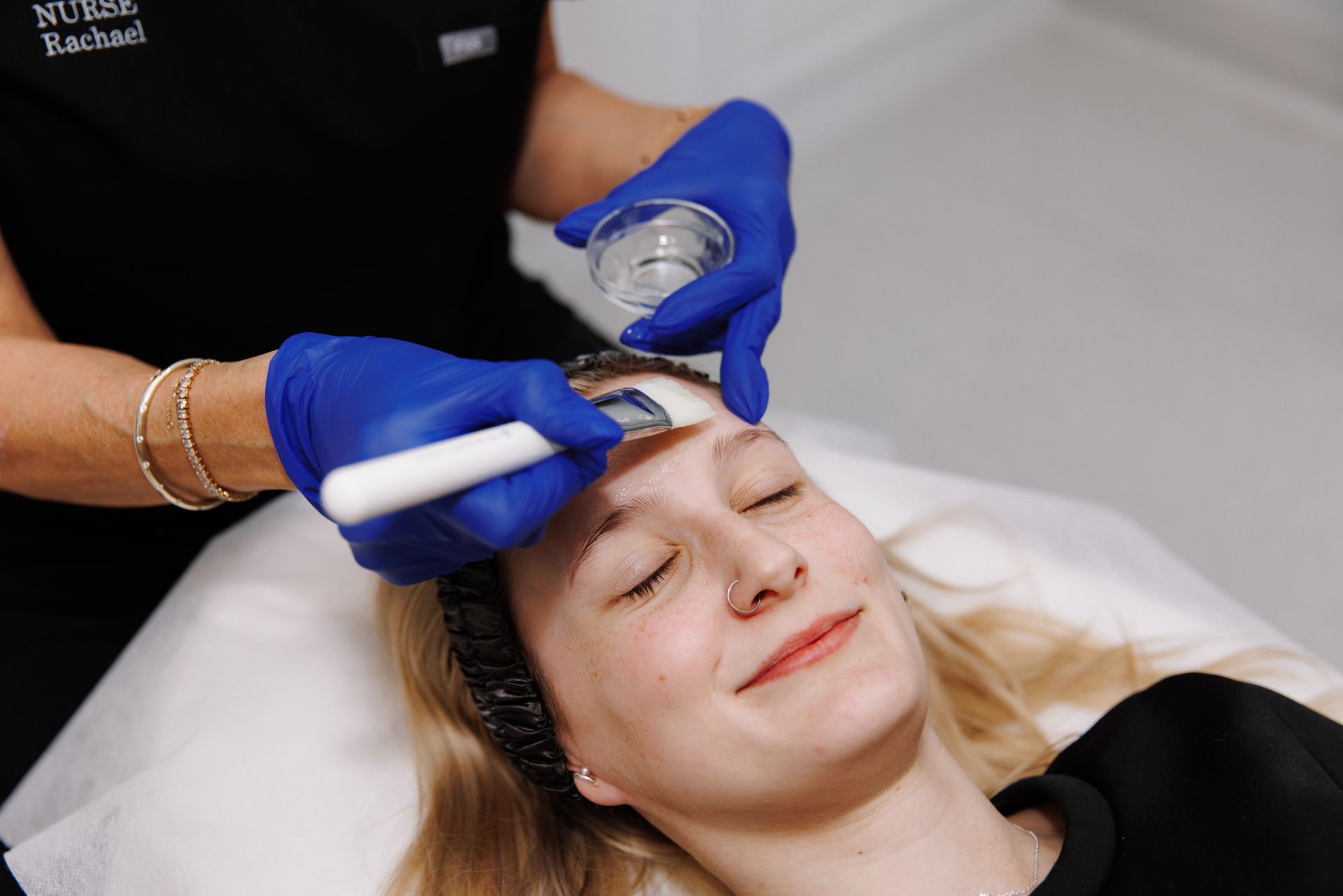 A Woman is Getting a Facial Treatment With a Roller on Her Face — Renew Laser Clinic in Taree, NSW
