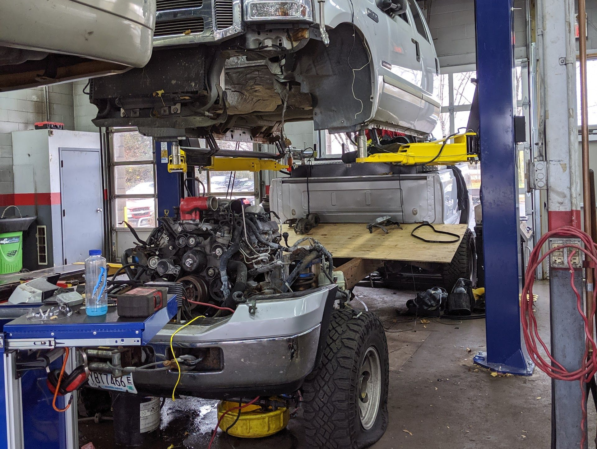 A mechanic’s shop with a truck body lifted on a car hoist, revealing the engine exposed below | Homestead Auto & Tire