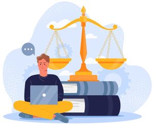 A man is sitting on the floor with a laptop in front of a scale of justice.