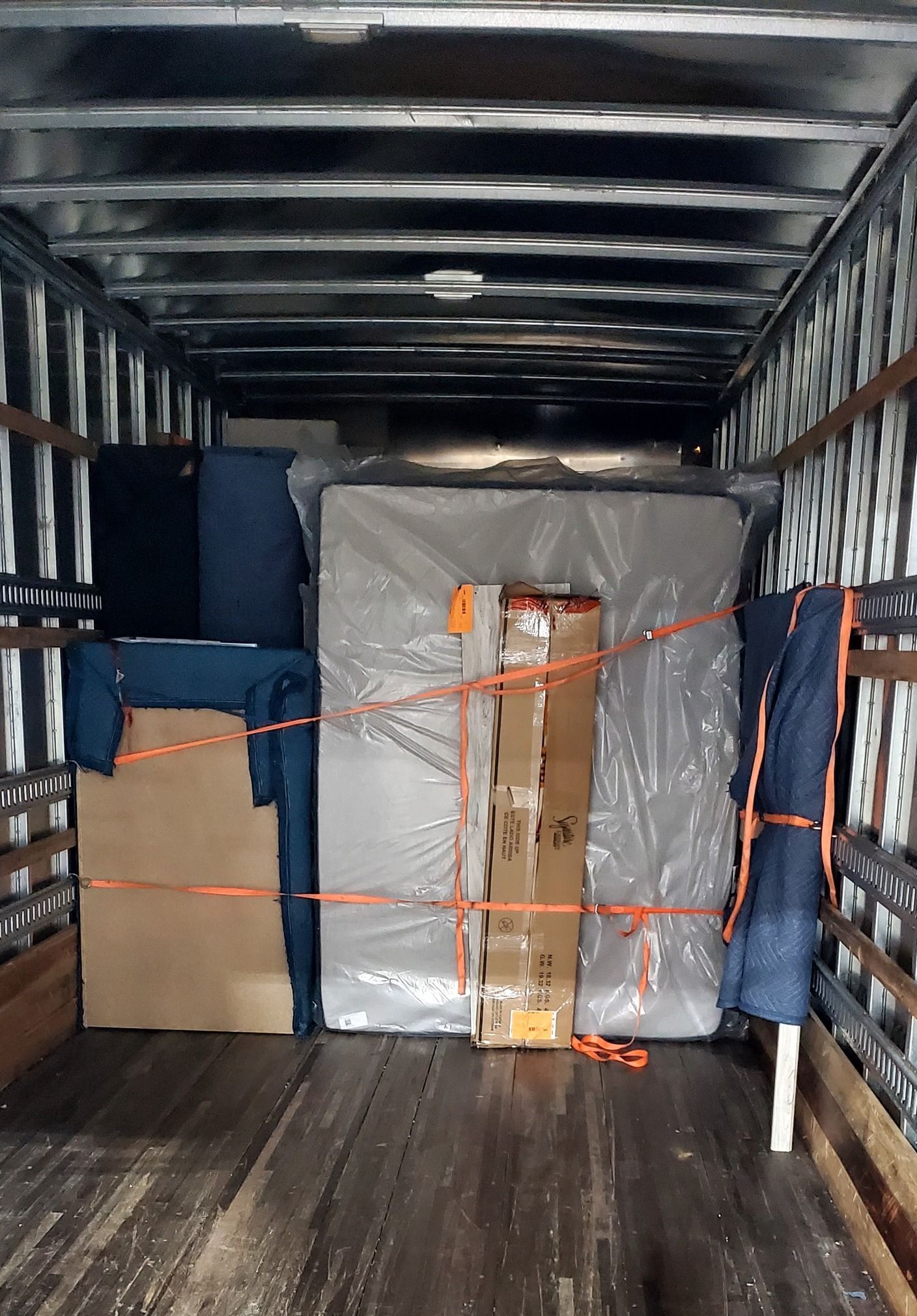 The inside of a moving truck filled with boxes and mattresses.