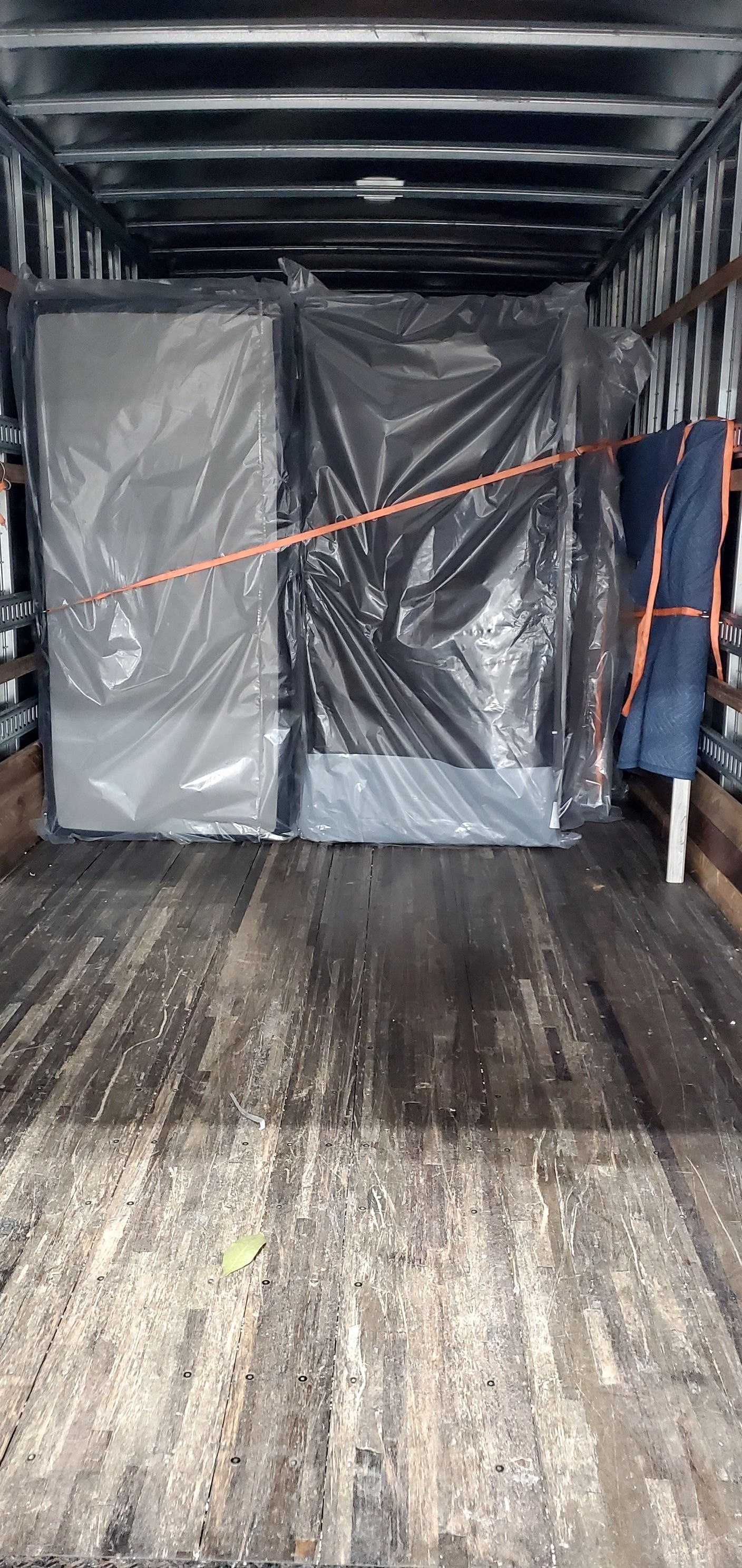 A mattress is wrapped in plastic in the back of a moving truck.