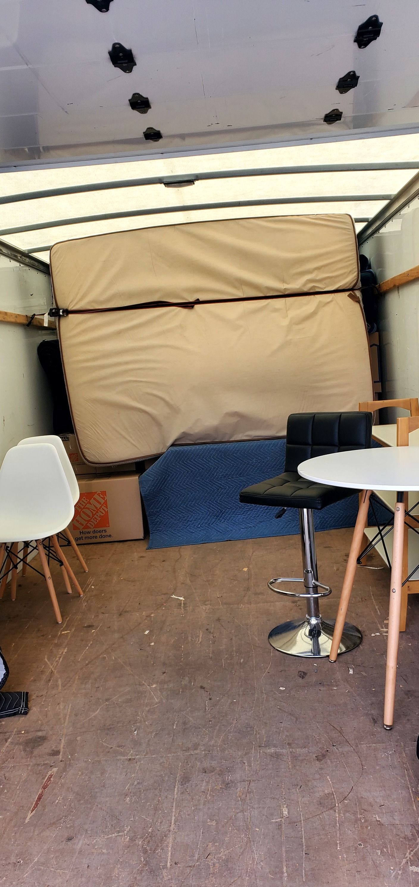 A mattress is sitting on top of a table in the back of a moving truck.