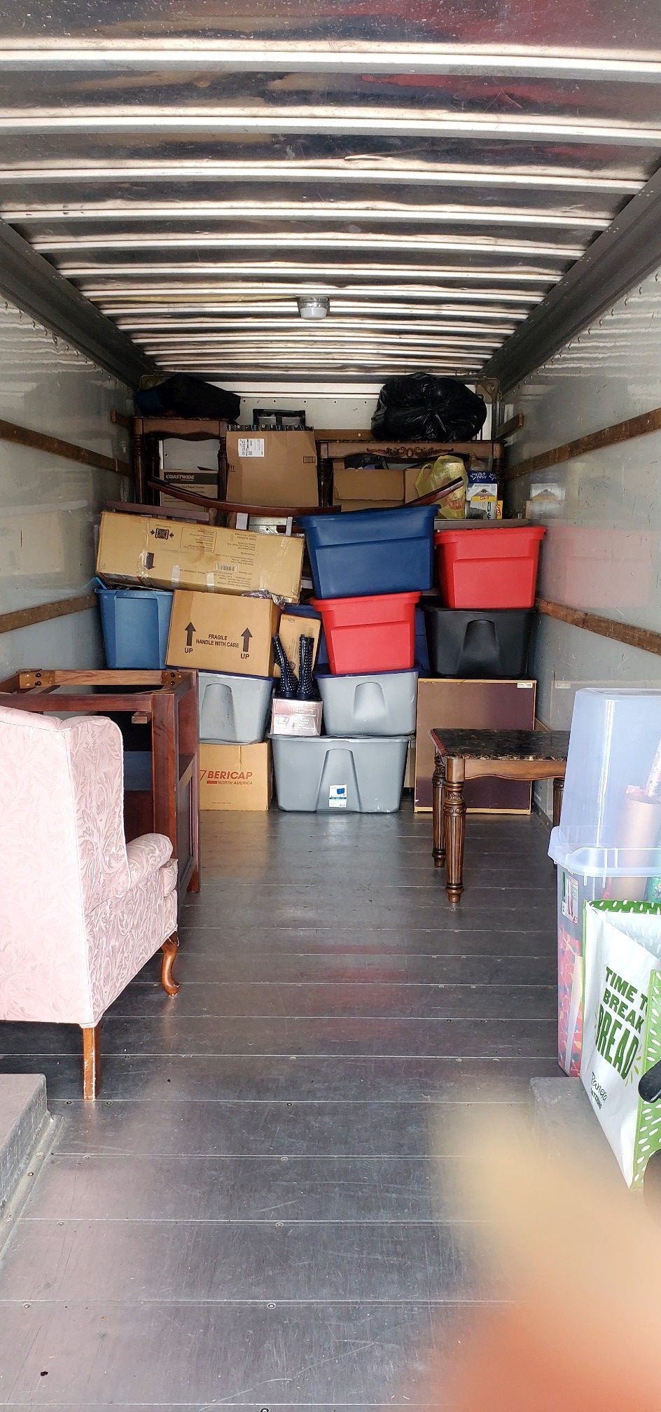 The inside of a moving truck filled with boxes and chairs.