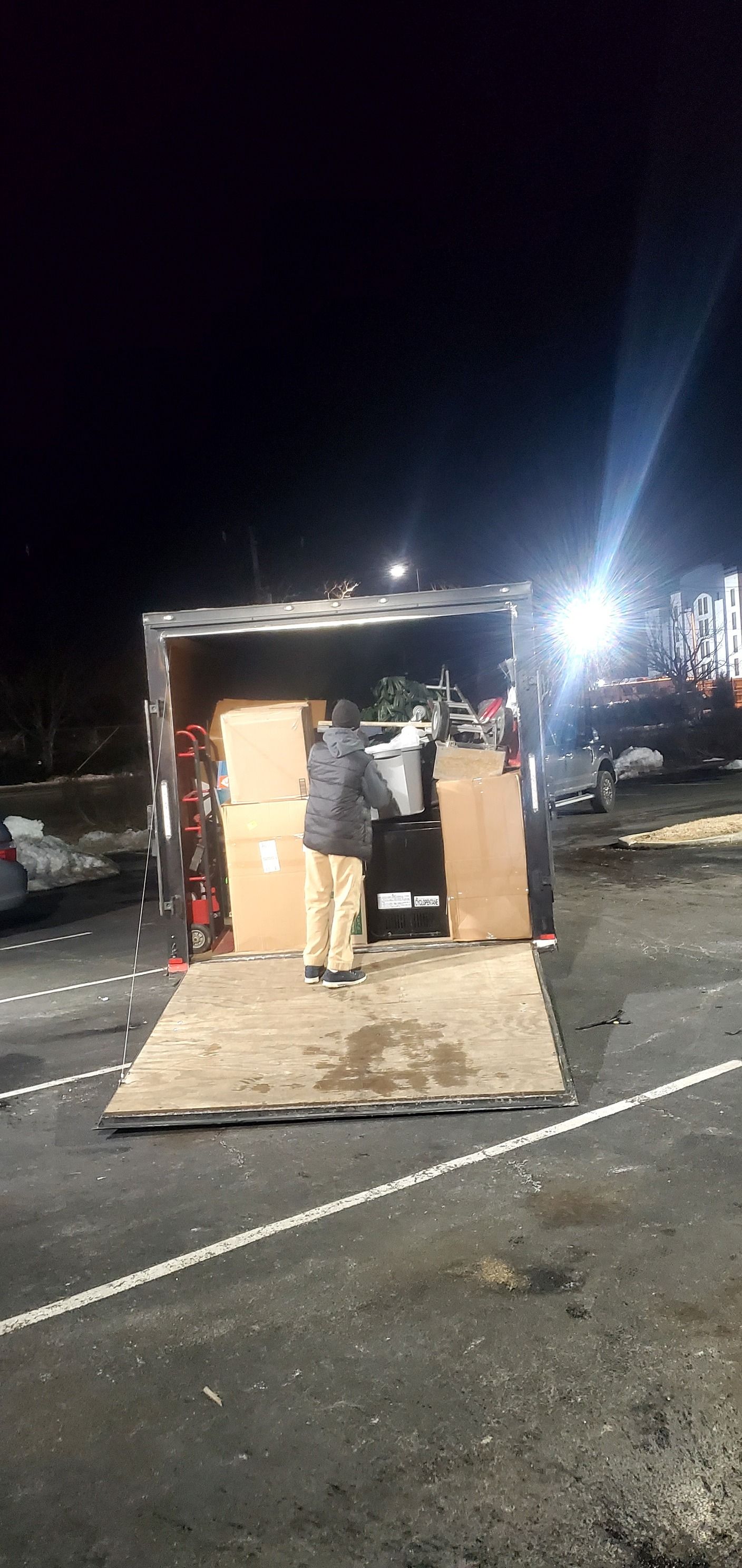 A man is loading boxes into a truck at night.