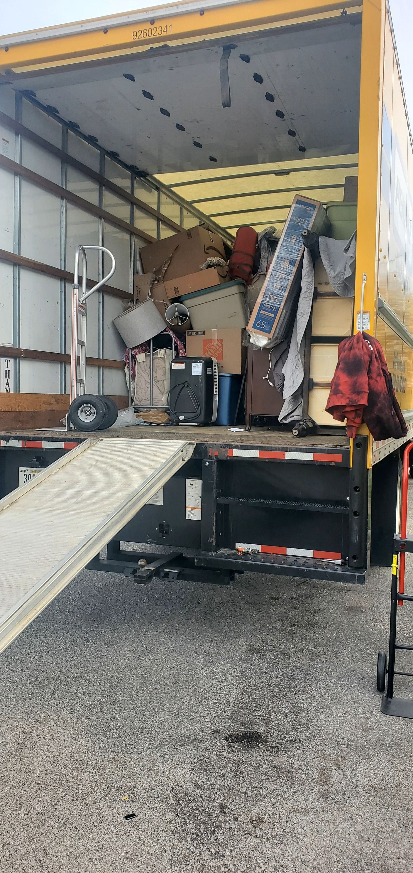 A moving truck filled with lots of junk and a ramp.
