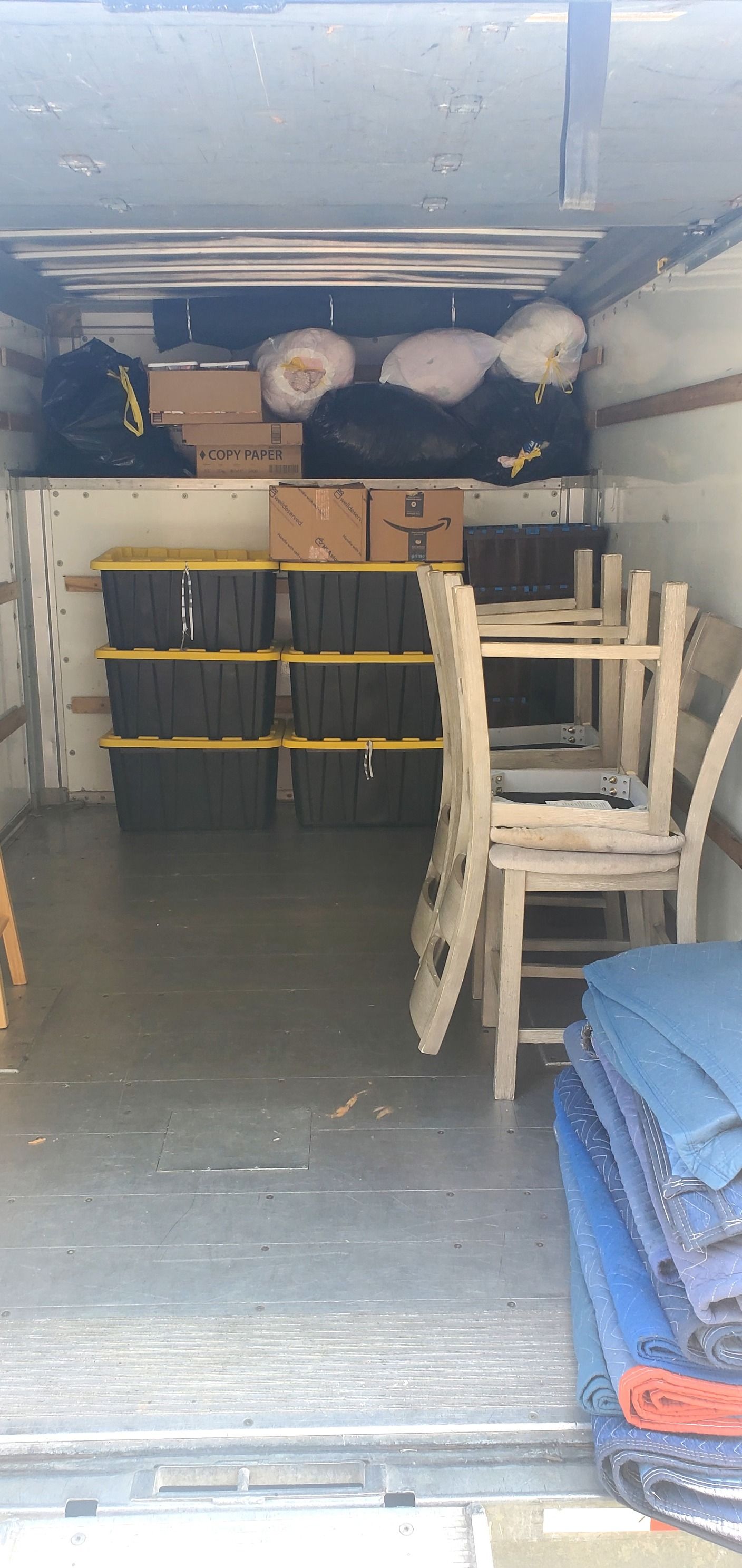 The inside of a moving truck filled with furniture and boxes.