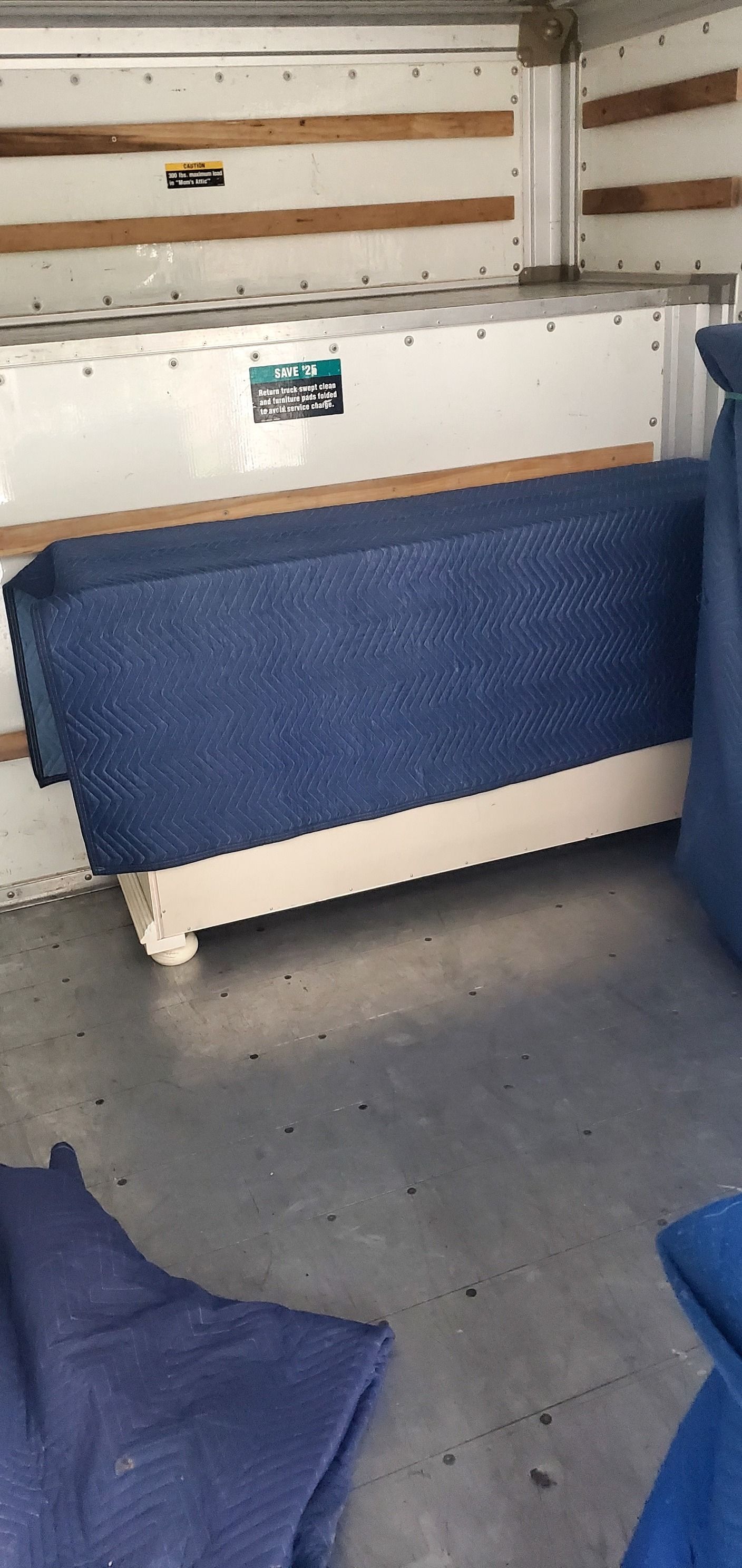 A blue couch is sitting in the back of a moving truck.