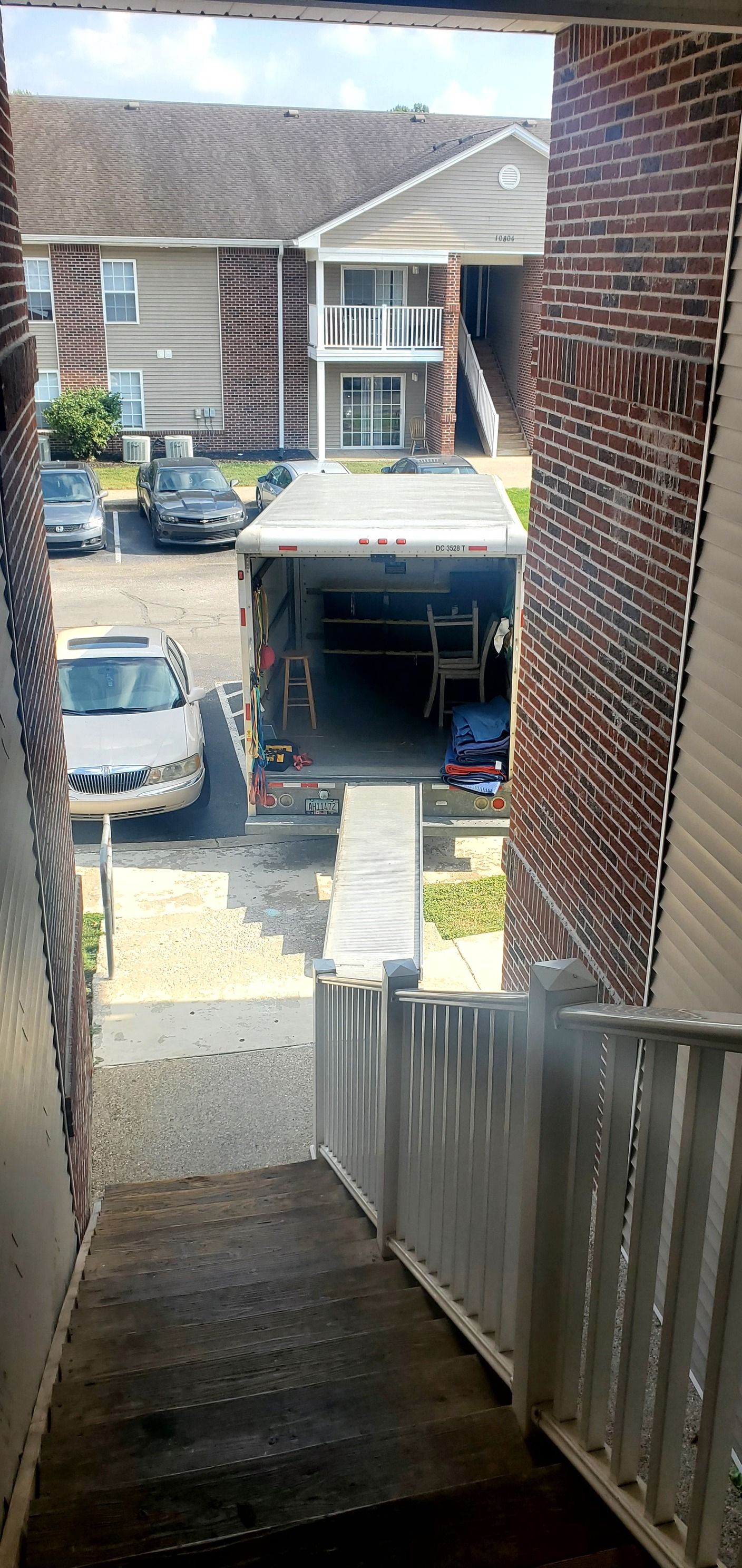 A truck is being loaded into a garage next to a brick building.