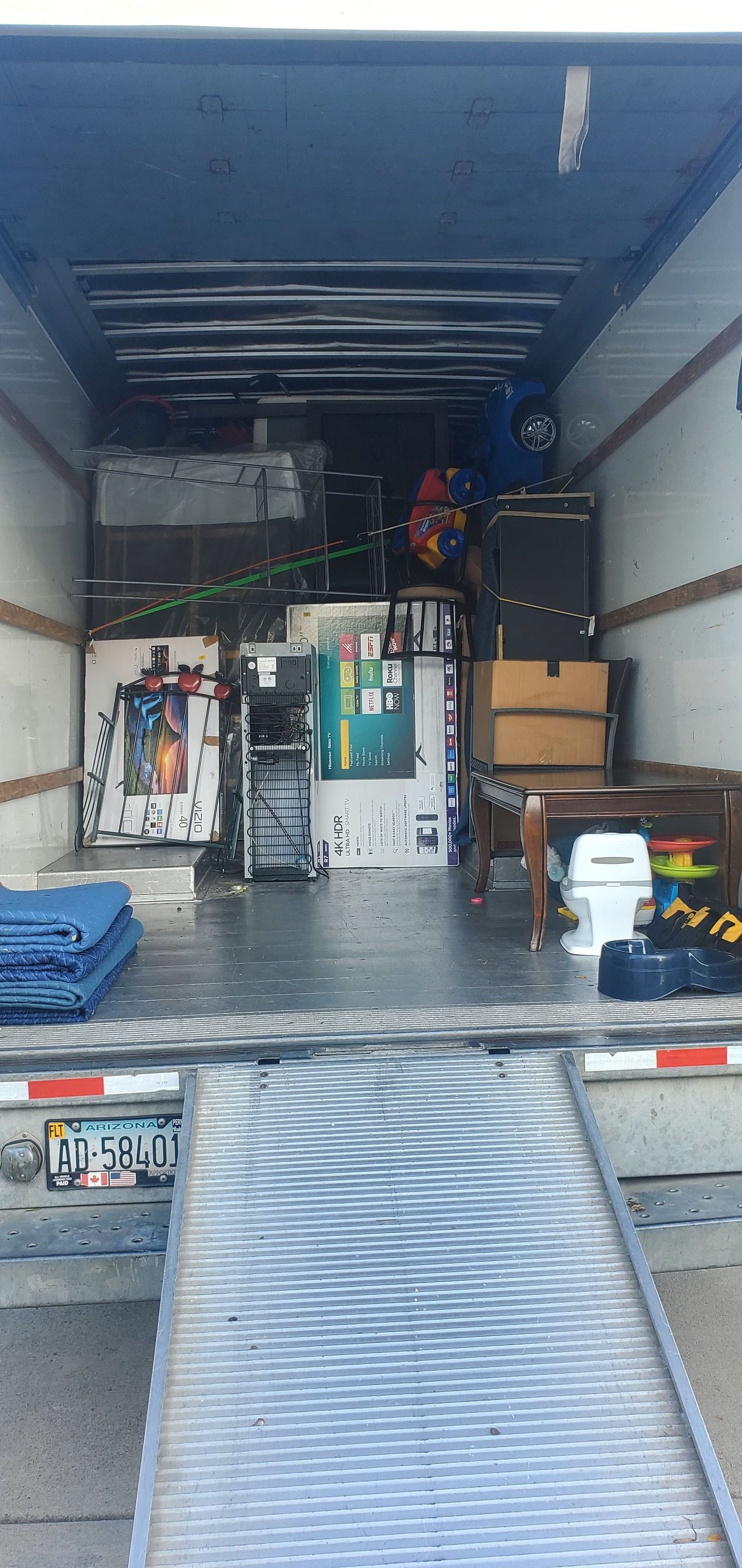 The inside of a moving truck filled with furniture and a ramp.