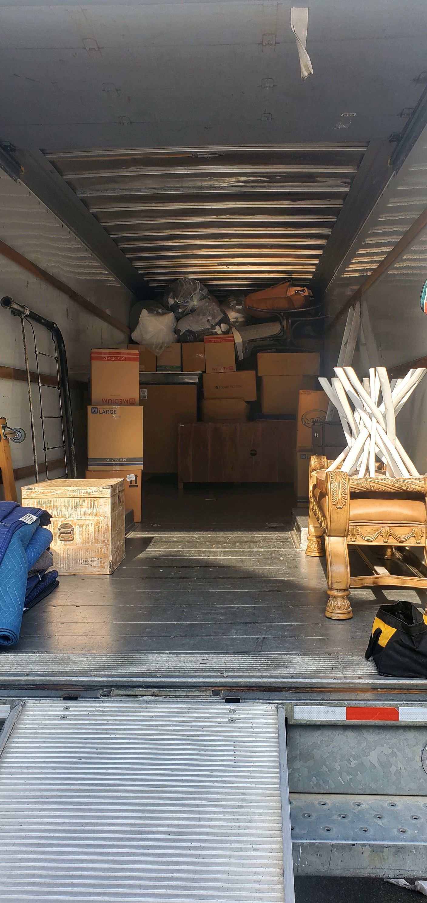 The back of a moving truck filled with boxes and chairs.