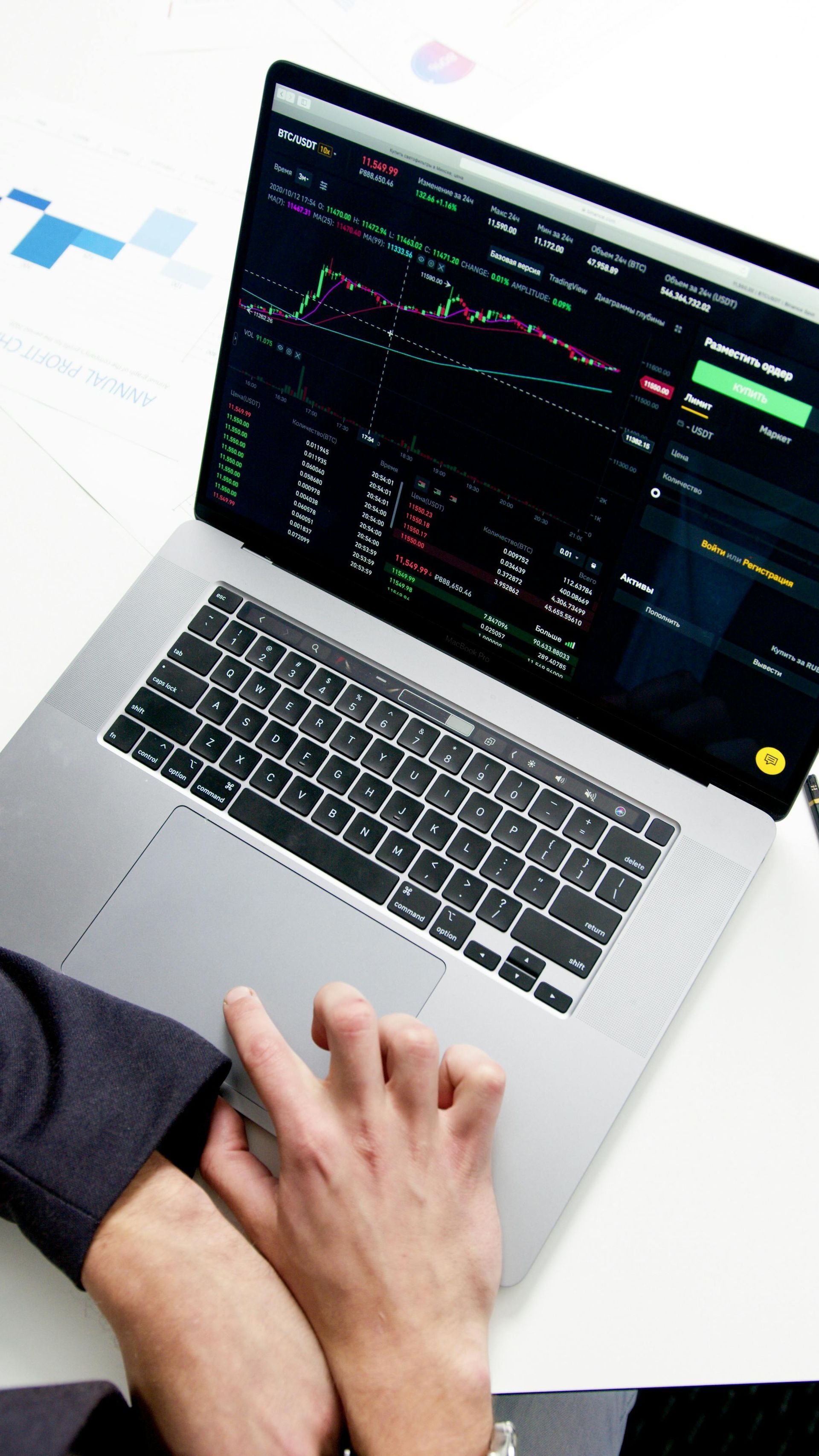 A person is typing on a laptop computer with a graph on the screen.