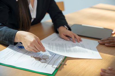 A woman is sitting at a table signing a document.