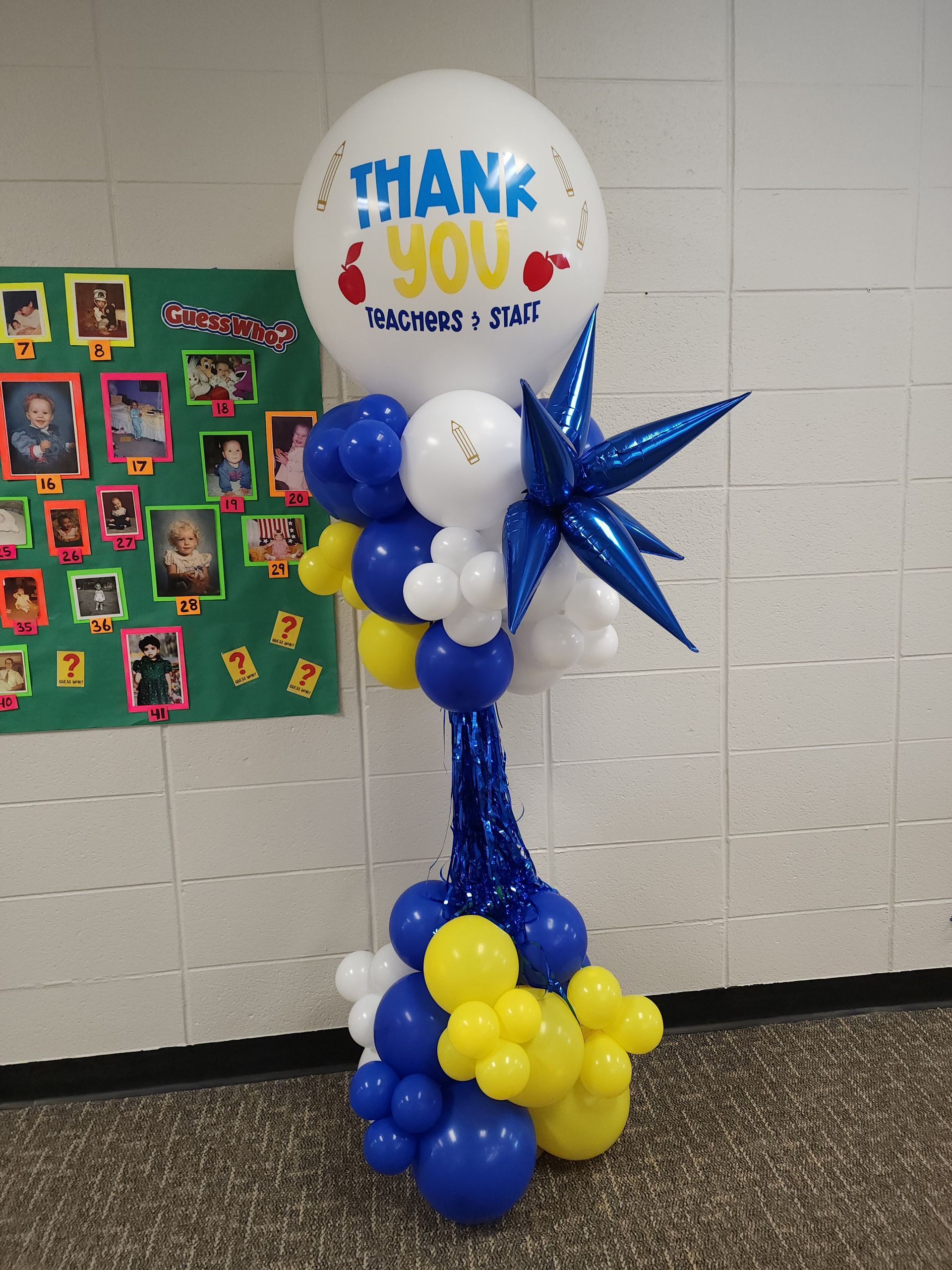 A thank you balloon is surrounded by blue and yellow balloons