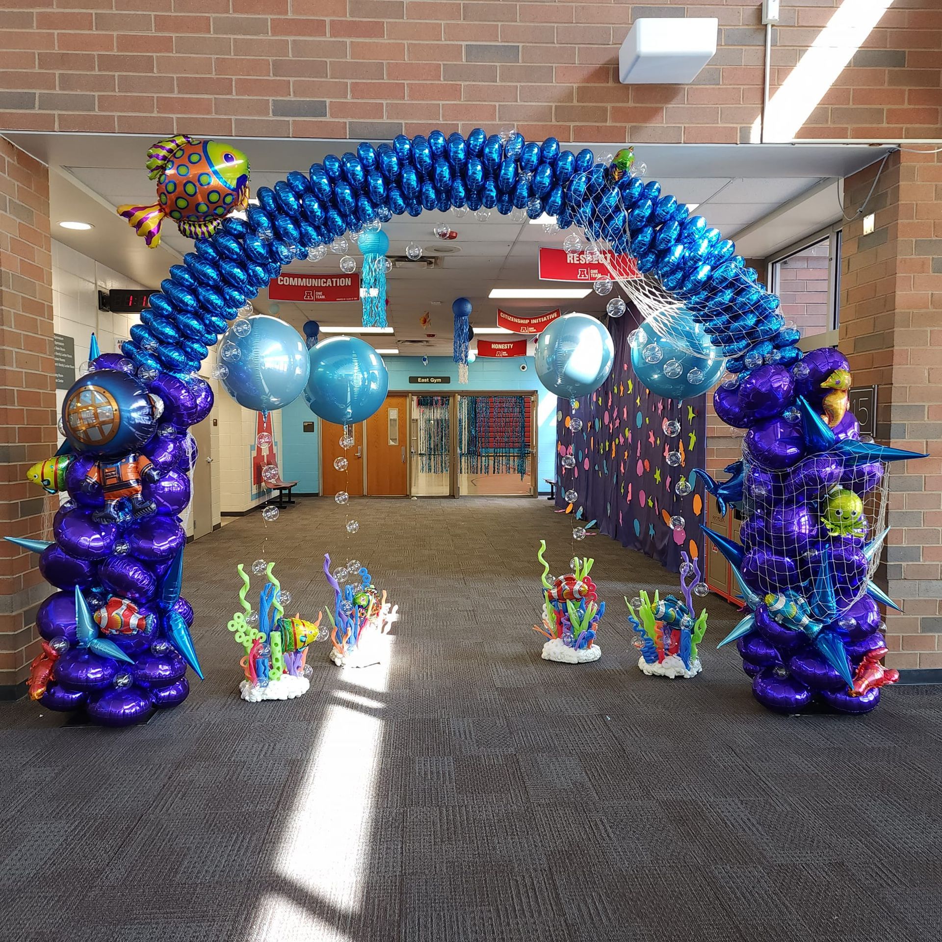 A hallway is decorated with blue and purple balloons