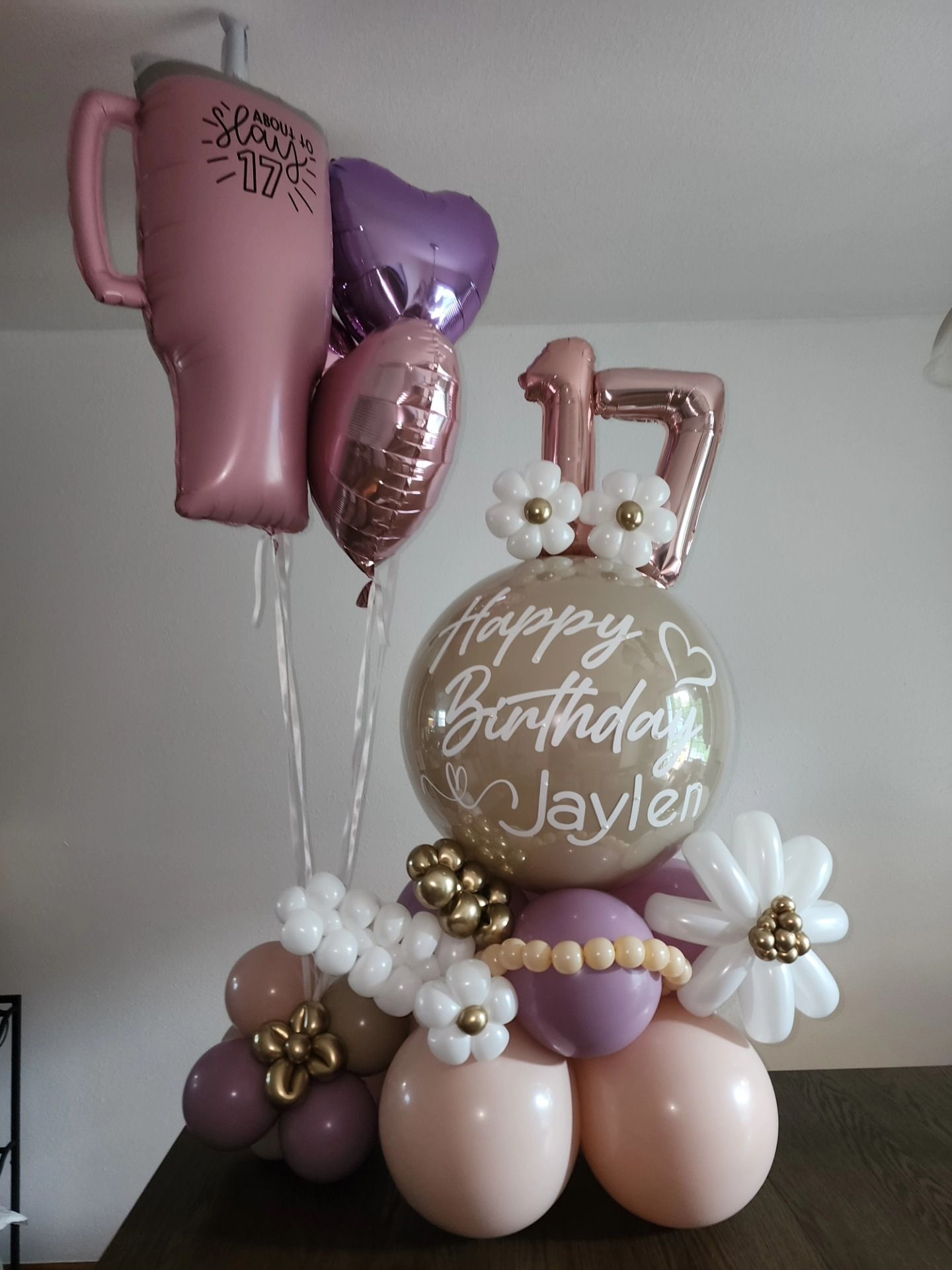 A bunch of pink and silver balloons are sitting on a wooden floor.