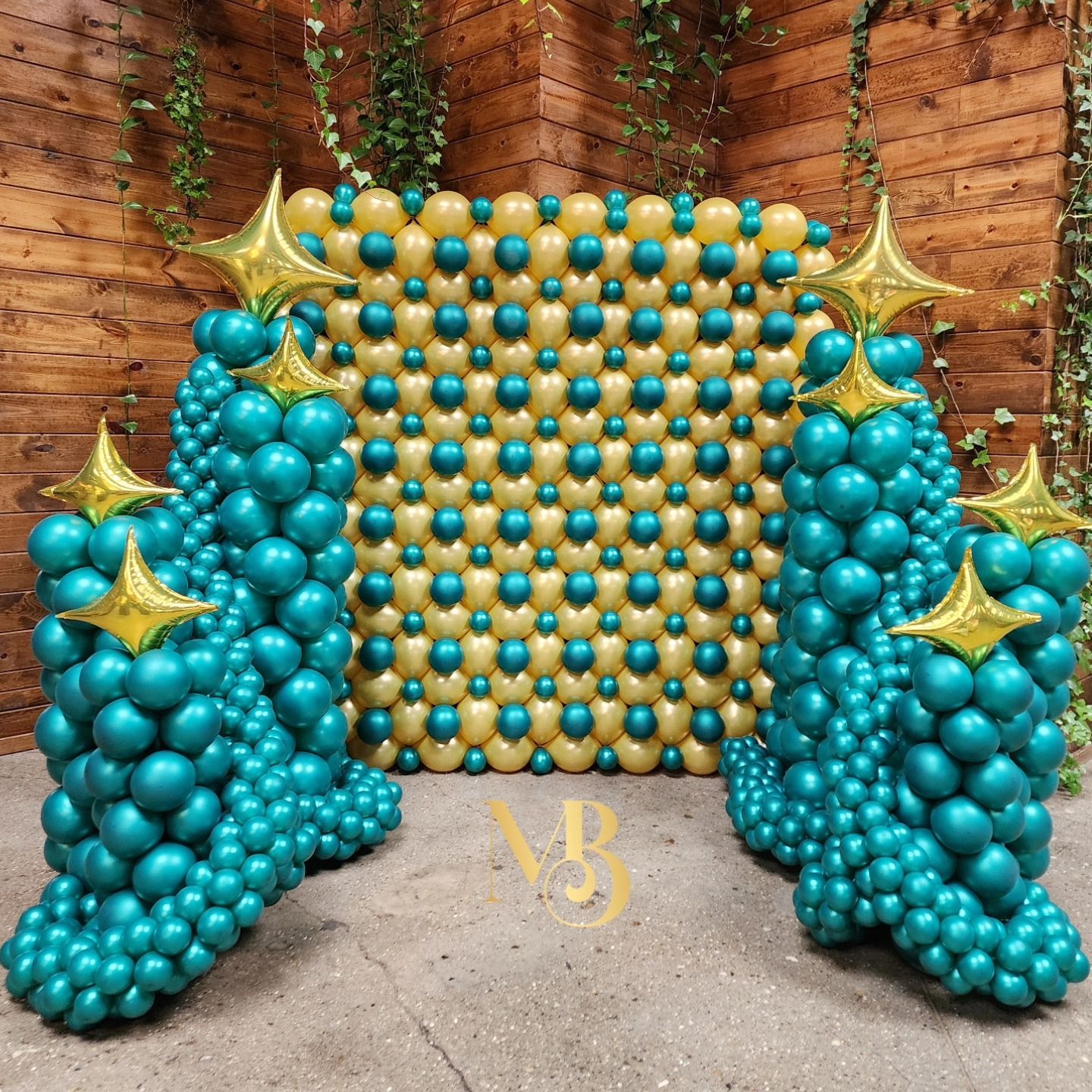 A wall of red , white , and blue balloons sitting on top of a lush green field.