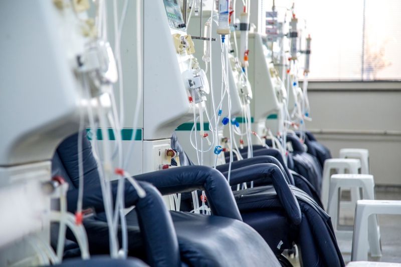 Room full of dialysis machines with wires and tubes hanging down from each machine. Comfortable blue seats waiting for patients to arrive.