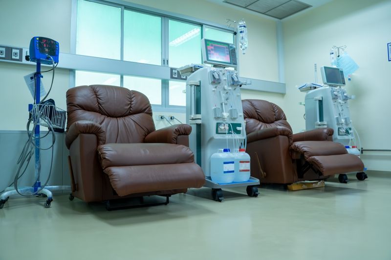 A row of empty dialysis chairs in a hospital room.