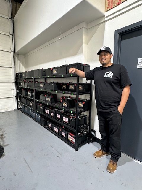 A man is standing in front of a shelf full of batteries.