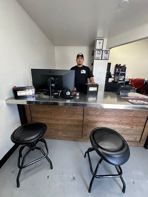 A man is standing behind a counter in front of a computer.