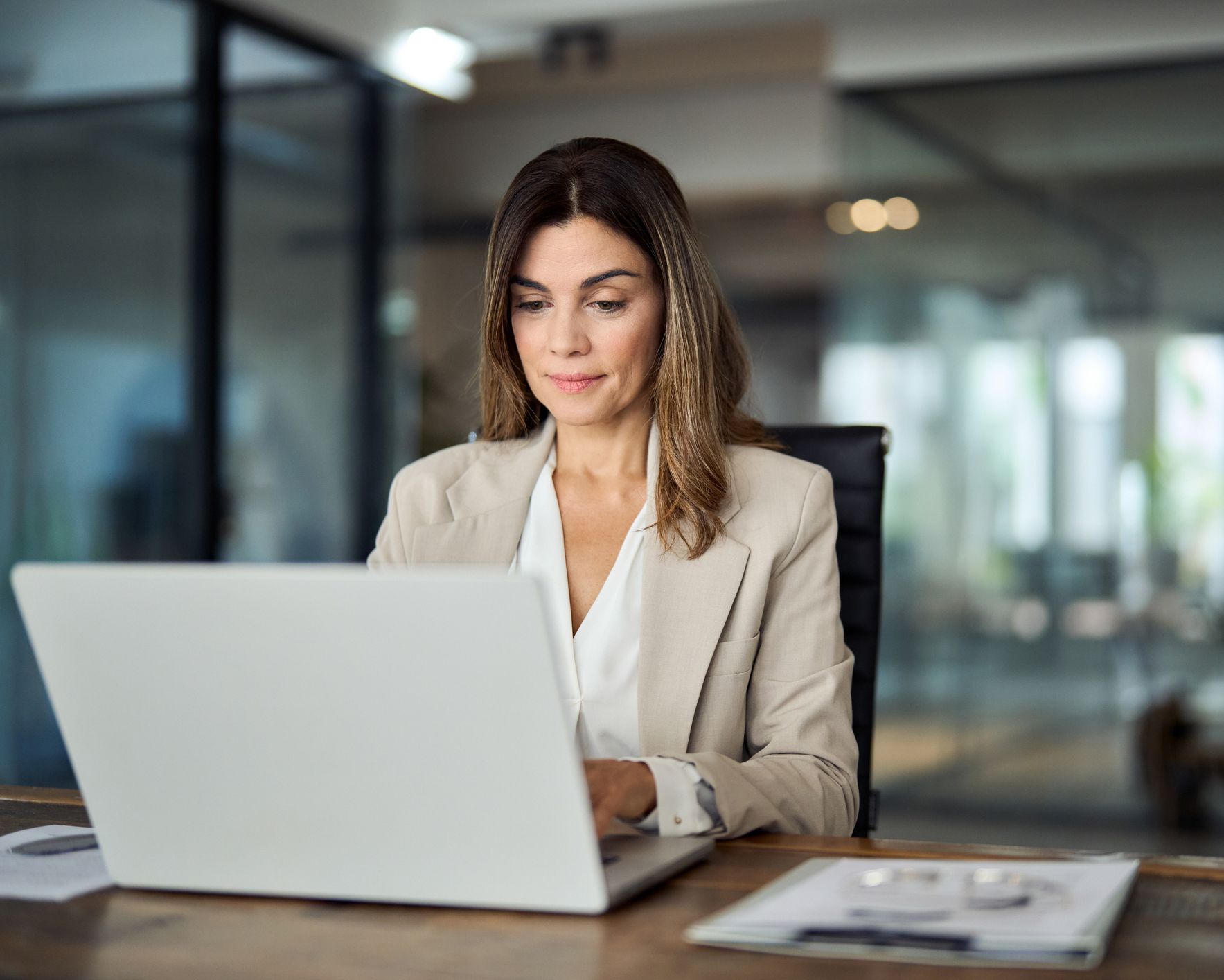 A woman is sitting at a desk using a laptop computer.