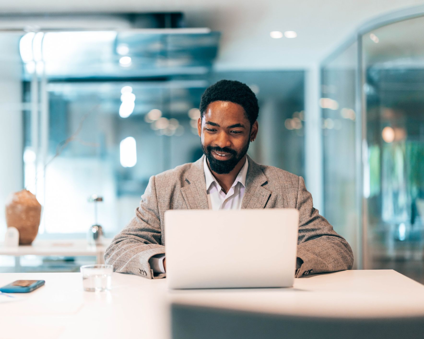 A man is sitting at a table using a laptop computer.
