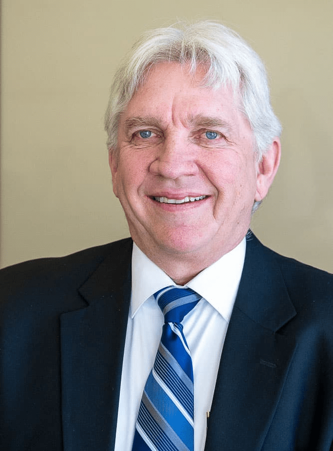 A man in a suit and tie is smiling for the camera