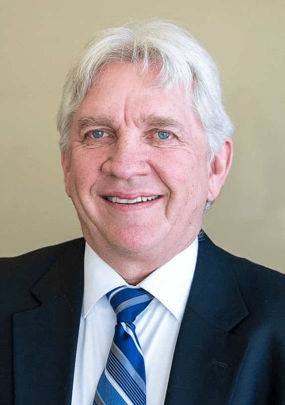 A man in a suit and tie is smiling for the camera