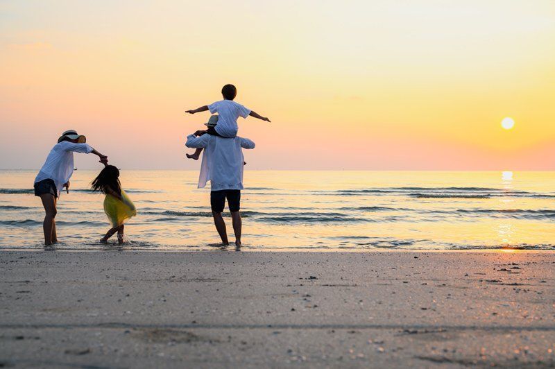 A family is walking on the beach at sunset.