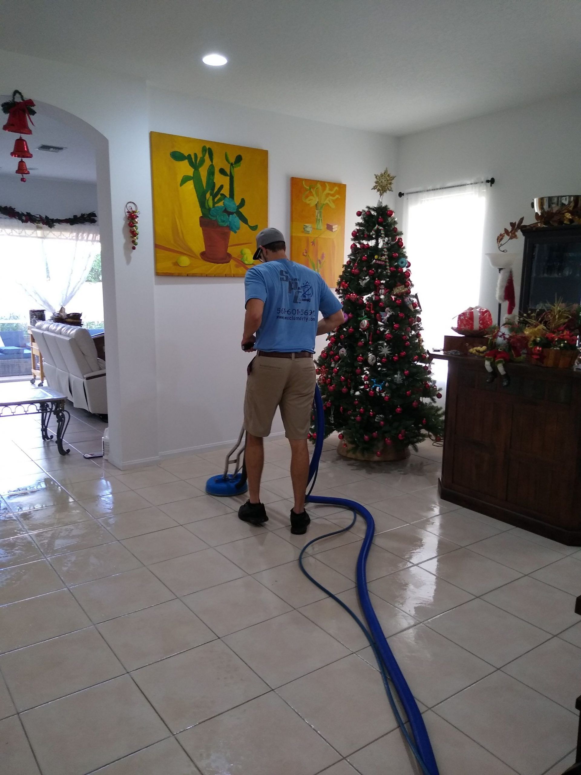 A man is cleaning the floor of a living room with a vacuum cleaner.