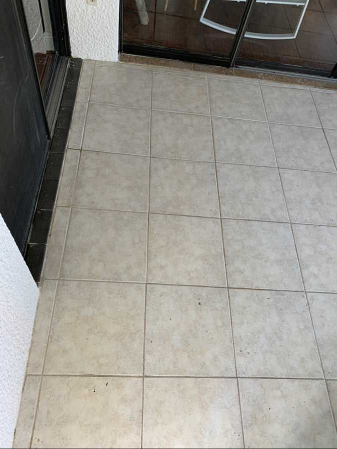 A tiled floor in a room next to a door.