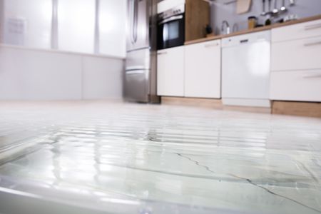 A kitchen with a flooded floor and a sink.
