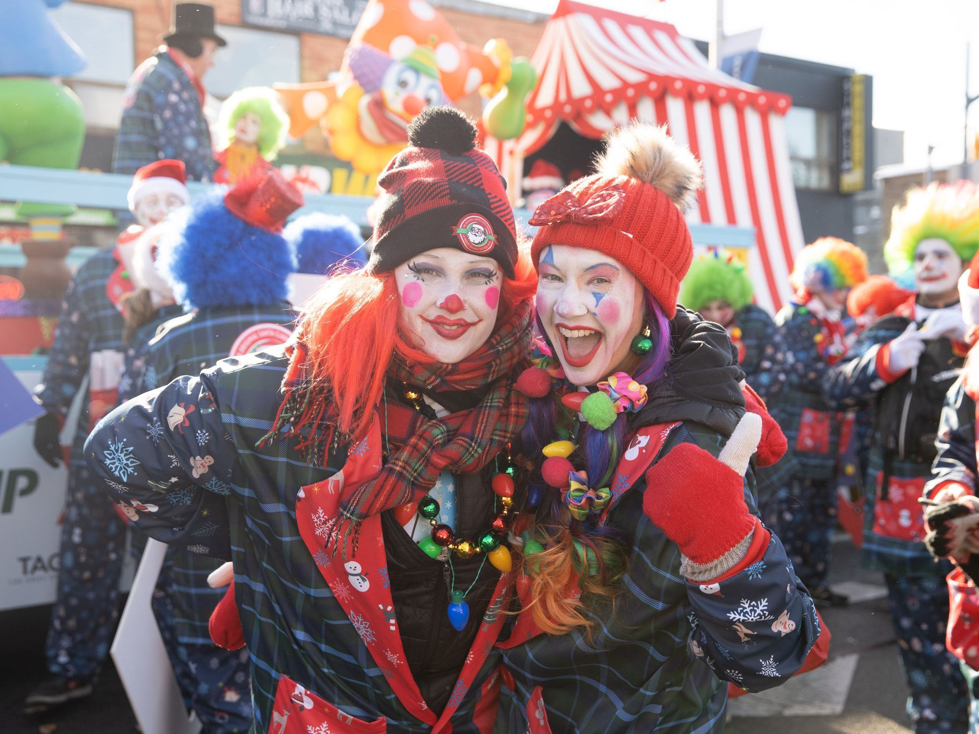 Two women dressed as clowns are posing for a picture in a parade.