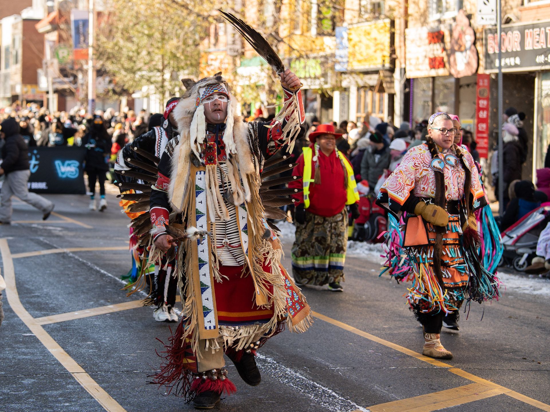 A group of people in native american costumes are walking down a street.