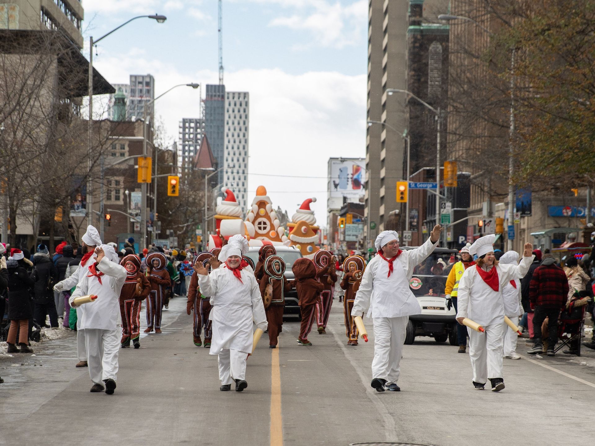 A group of people in chef 's hats are marching down a city street