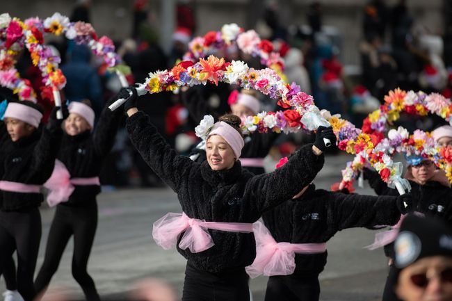 A group of young girls are holding flowers in their hands in a parade.