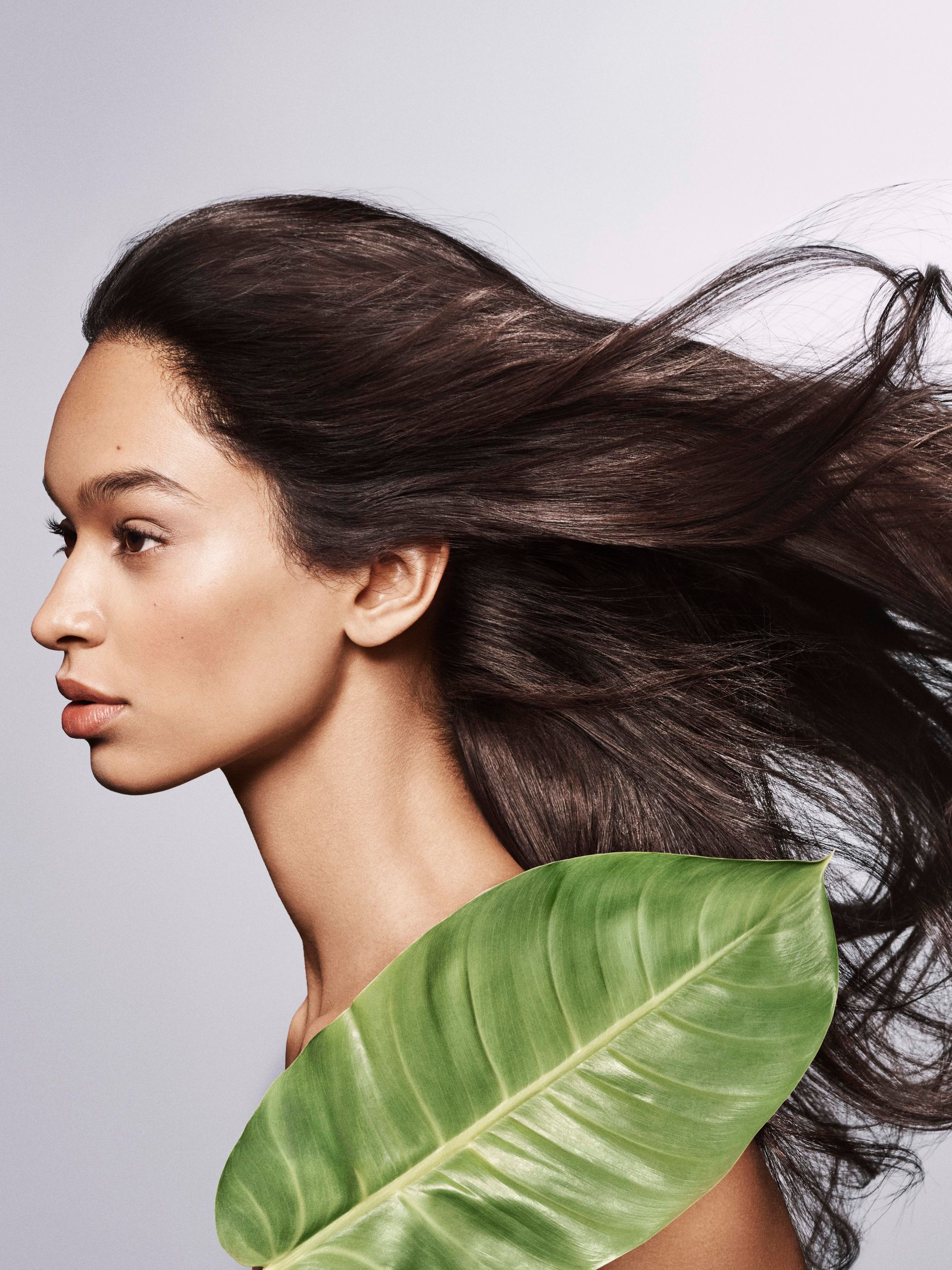 Woman with curly dark hair, wearing white dress, looking at the camera, framed by a circular opening.