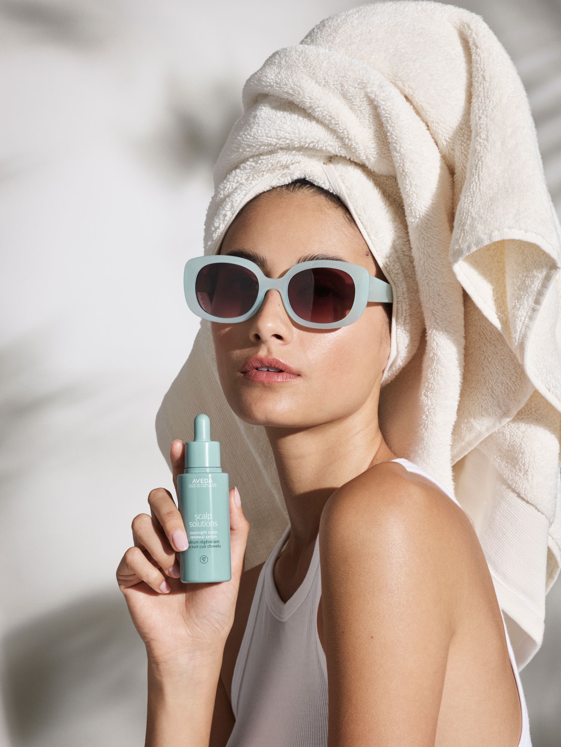 Woman with light skin, light brown hair, looking towards the camera, hands clasped in front.