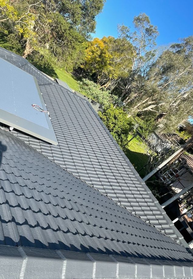 A Roof With a Solar Panel on It and Trees in the Background — Platinum Pride Roofing In Wyoming, NSW