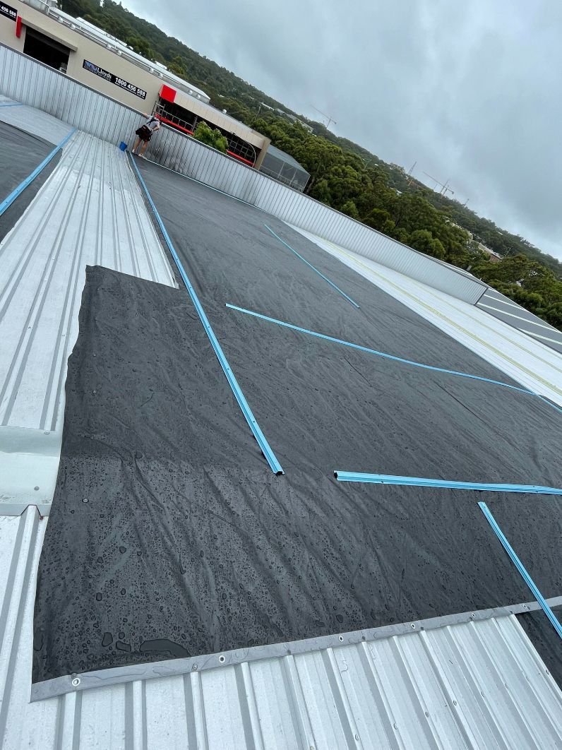 A Person is Working on the Roof of a Building — Platinum Pride Roofing In Terrigal, NSW
