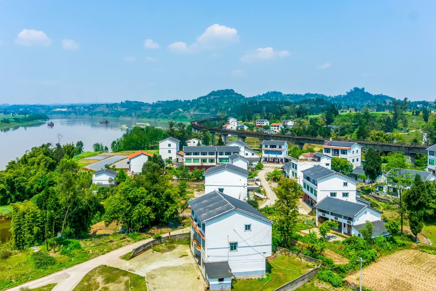 An aerial view of a small village with a river in the background.