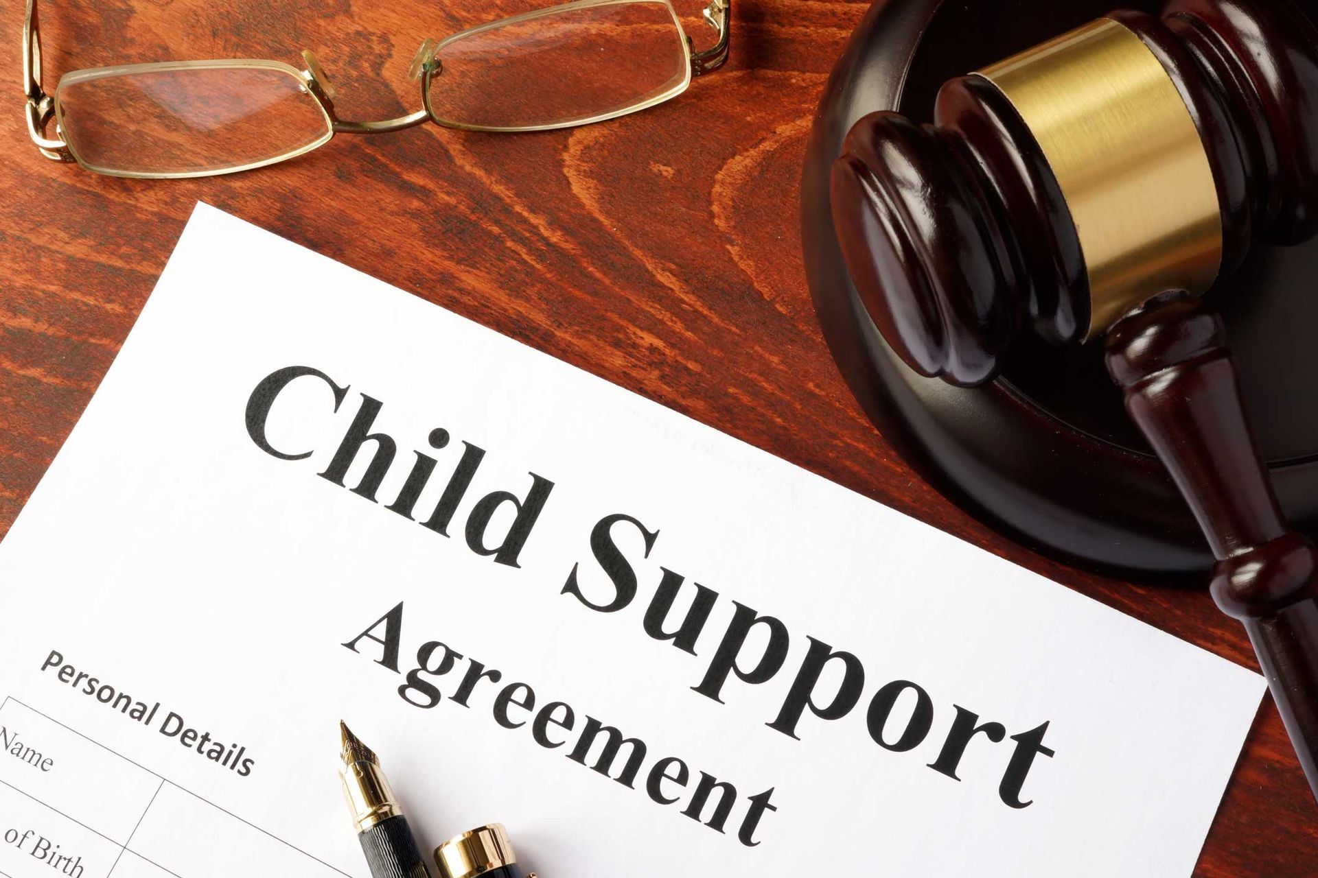 Child Support Agreement document with gavel and glasses on a wooden desk.