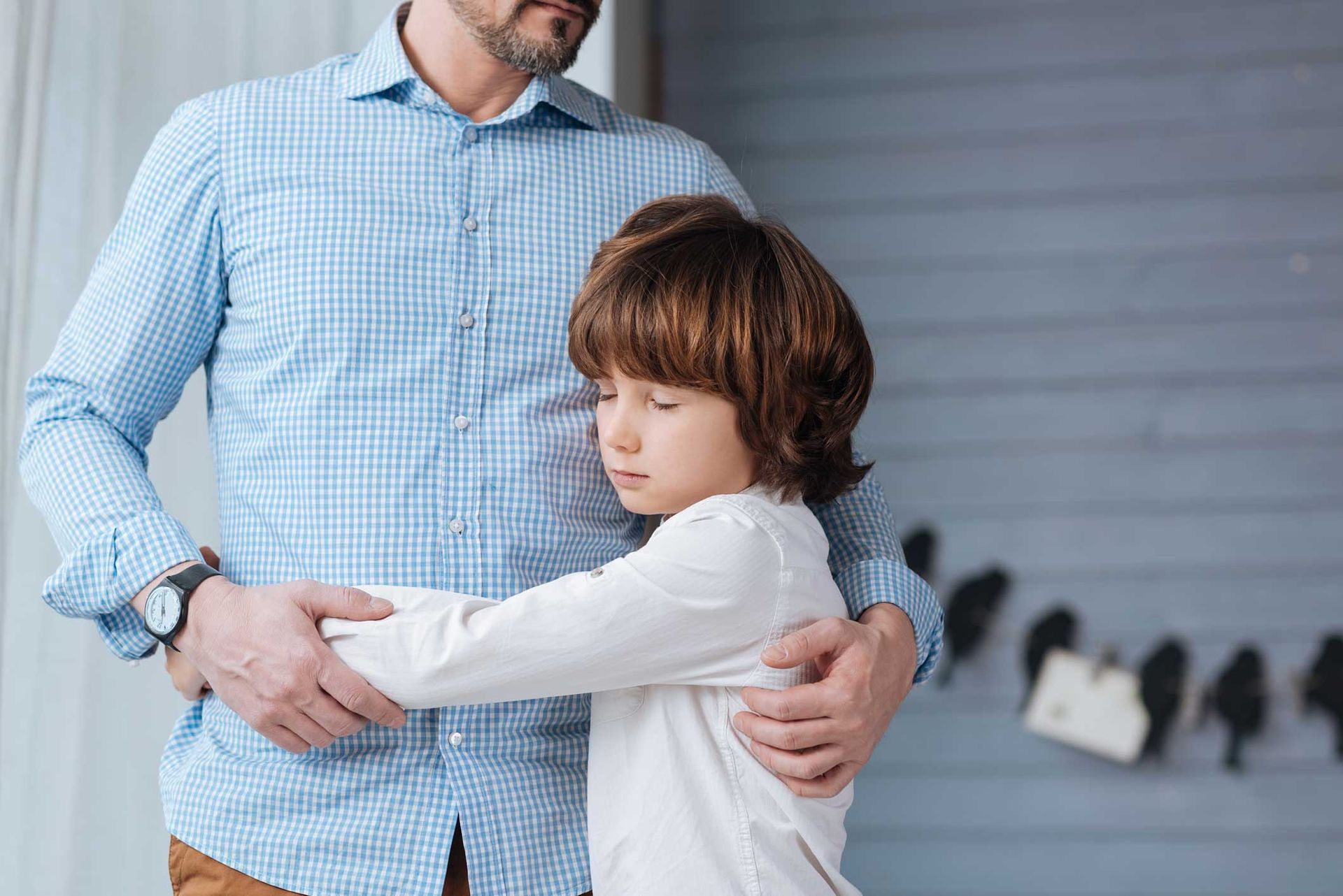 Man in blue shirt hugging a child who is burying his face in the man's chest. Man in blue shirt hugging a child who is burying his face in the man's chest.