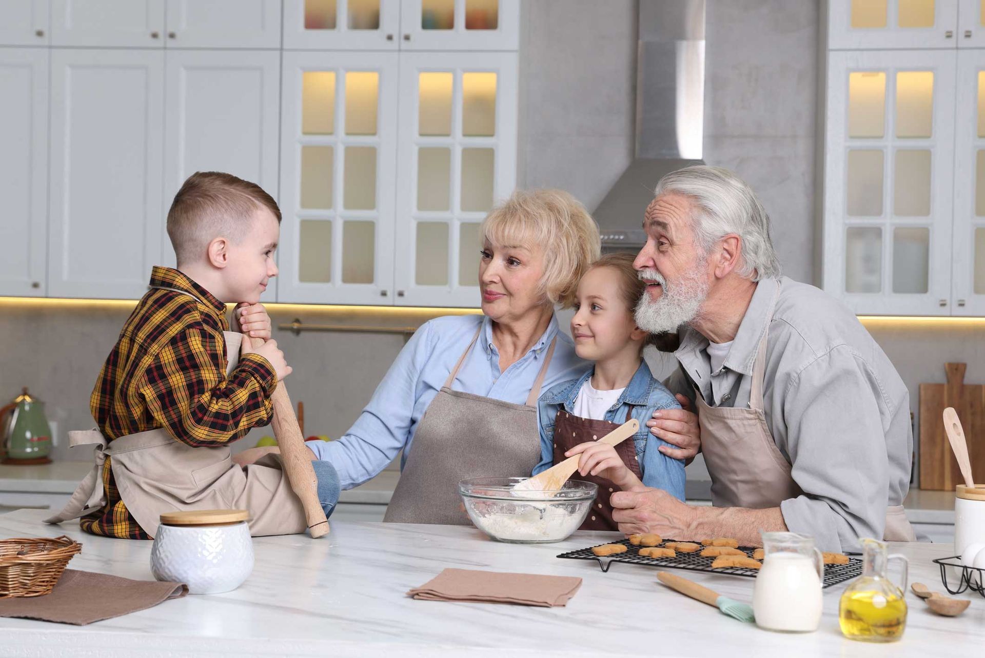 Family baking together in a bright kitchen: grandparents, boy, and girl smiling. Family baking together in a bright kitchen: grandparents, boy, and girl smiling.
