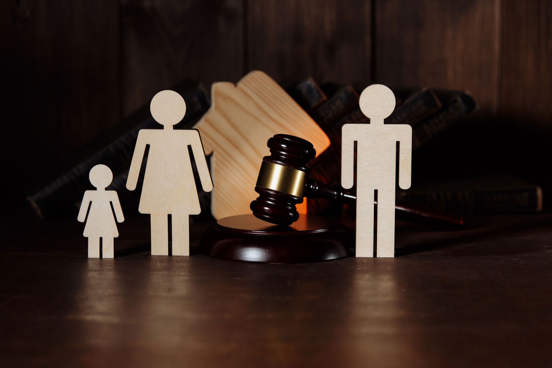 Wooden figures of a family and home with a gavel, symbolizing legal proceedings.