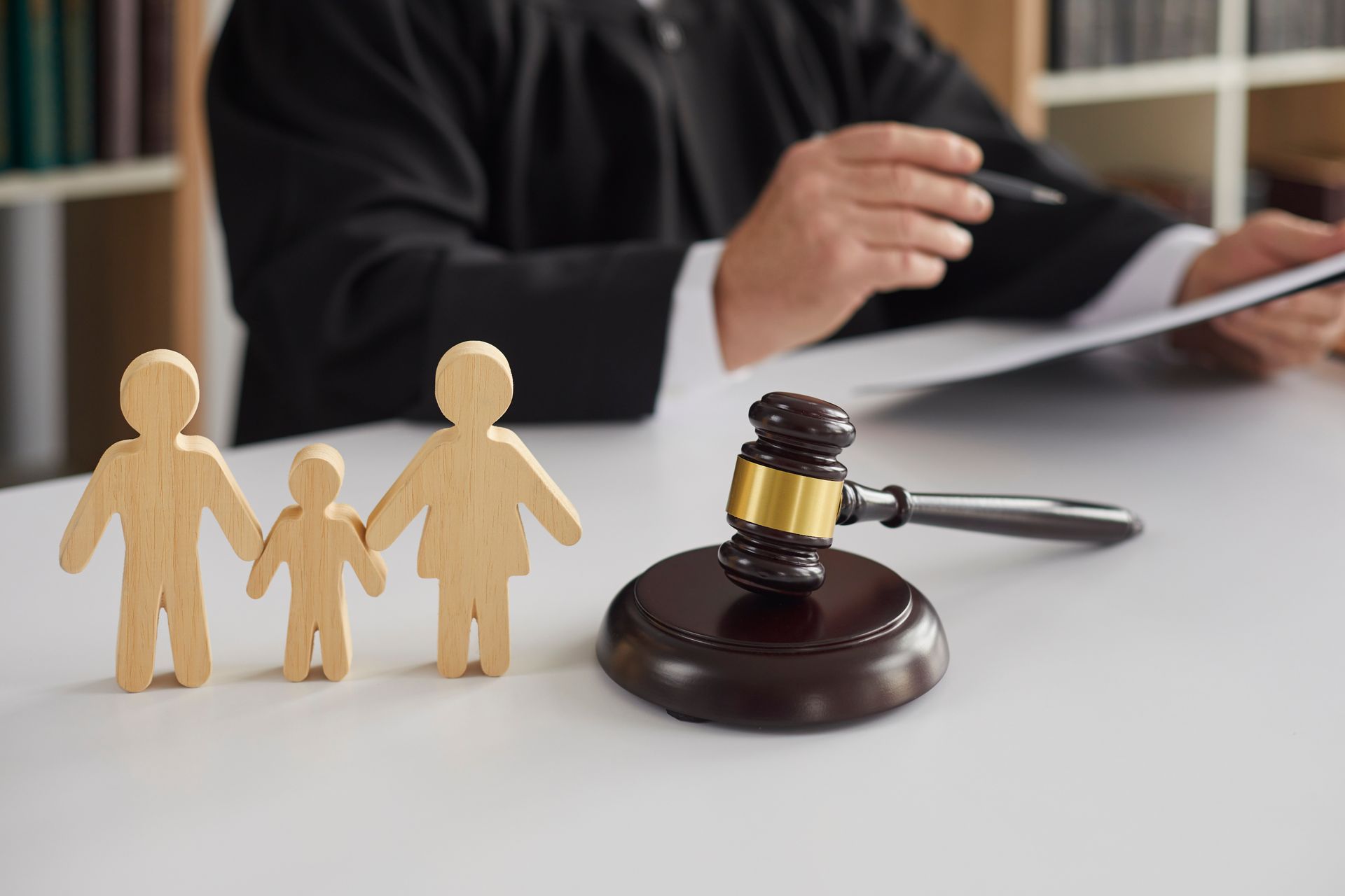 Paper family figures on a book with a gavel, symbolizing family law. Paper family figures on a book with a gavel, symbolizing family law.
