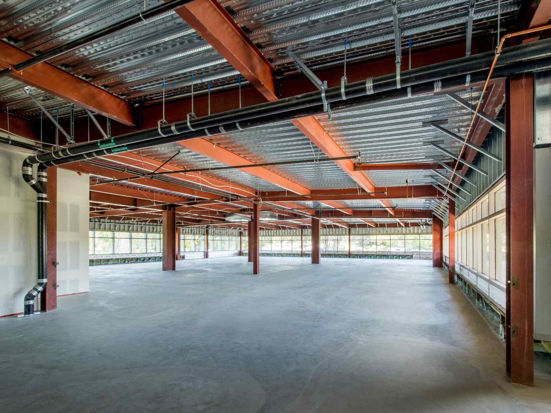 A large empty building with a lot of pipes hanging from the ceiling.