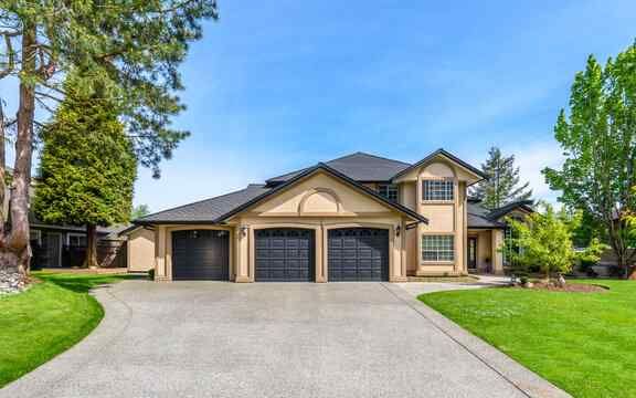 A large house with two garages and a driveway leading to it.