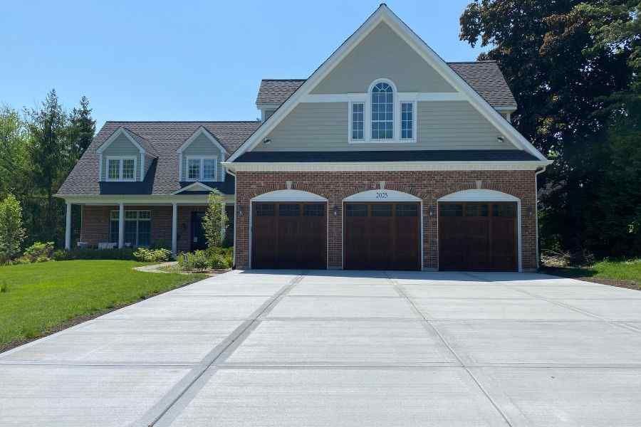 A large brick house with three garage doors and a concrete driveway