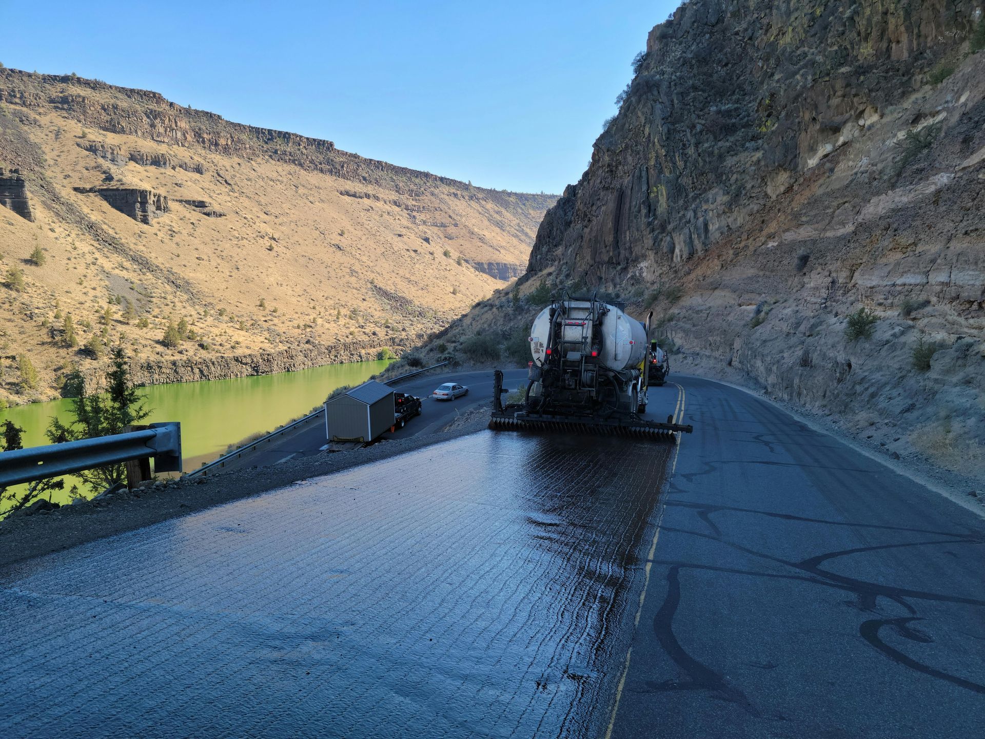 A truck is driving down a road next to a river.
